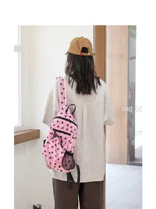 Vista detallada de una mochila de nailon rosa con lunares negros llevada por una modelo
