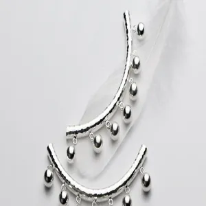 Dettaglio ravvicinato di tubo curvo martellato in argento sterling S925 con campanelli