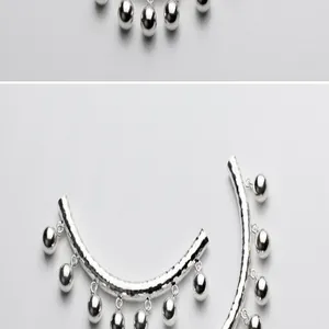 Primo piano del tubo curvo in argento sterling S925 con campanellini pendenti