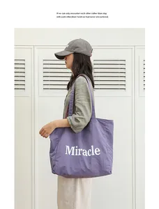 Bolso tote casual de nailon morado con estampado Miracle en el hombro de una modelo
