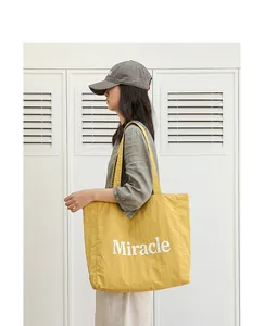 Vista detallada del bolso tote de nailon amarillo con estampado Miracle en una modelo