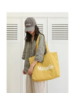 Elegante bolso tote de nailon amarillo con estampado Miracle en un entorno informal
