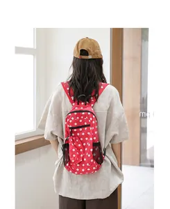 Vista trasera de una elegante mochila de nailon roja con lunares blancos llevada por modelo