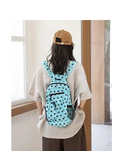 Mochila de moda de nailon azul con lunares negros y bolsillo de malla en la espalda del modelo