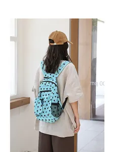 Vista trasera de una mujer que lleva una mochila de nailon azul claro con lunares en casa