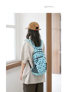 Vista trasera de una mochila de nylon azul con lunares usada en una sala clara