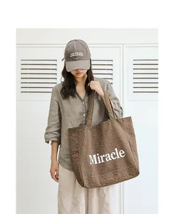 Modelo asiática con un bolso tote de cuadros marrones y estampado Miracle blanco