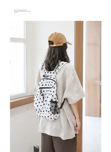 Vista de estilo de vida de mujer con mochila de nailon con lunares en sala luminosa