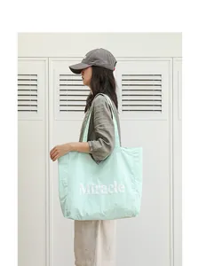 Vista detallada de un bolso tote de nailon verde claro con letras blancas de Miracle
