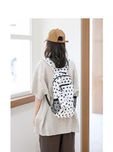 Modelo con una elegante mochila de nailon con lunares blancos y negros, vista posterior
