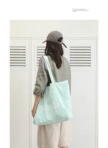 Vista posterior de modelo con un bolso de nailon verde menta con el estampado Miracle