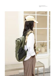 Modelo asiática luciendo una mochila informal de nailon verde oliva en estilo urbano