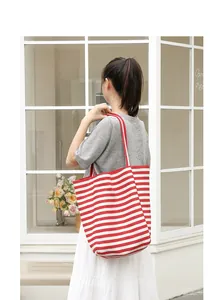 Detailed close-up view of a red and white striped canvas tote bag on an Asian model