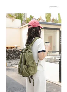 Green nylon drawstring backpack with grid pattern shown on model in lifestyle setting