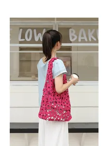 Lifestyle view of a magenta hollow-out flower lace shoulder bag with white inner pouch.