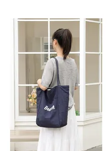 Detalle del bolso tote informal de nailon azul marino con elegante texto Beach blanco
