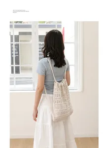 Vista trasera de mujer con mochila beige tejida calada con cordón en habitación soleada