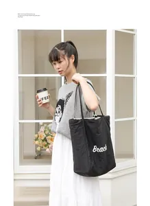 Vista de estilo de vida de un bolso tote de nailon negro con estampado 'Beach'