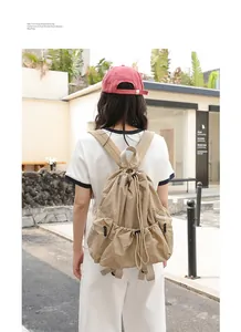 Back view of a casual beige plaid nylon drawstring backpack shown in an urban setting.