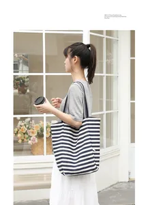 Side view of fashion model carrying a navy blue and white striped canvas tote bag