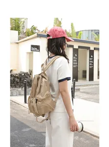 Model wearing khaki nylon drawstring backpack with subtle checkered texture in outdoor setting