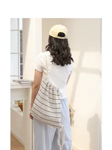 Detail eines gestreiften Strickbeutels mit Kordelzug, getragen von einem Modell in Freizeitkleidung.