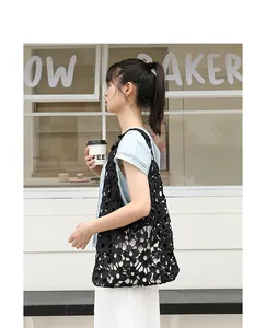 Fashionable black lace flower hollow-out shoulder bag styled by Asian model in cafe