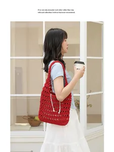 Lifestyle view of a red handmade crochet cotton shoulder bag with hollow-out design.
