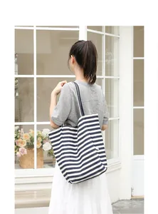 Back view of a woman carrying a stylish striped blue and white canvas tote bag