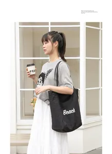 Elegante bolso tote de nailon negro con estampado Beach llevado por una modelo