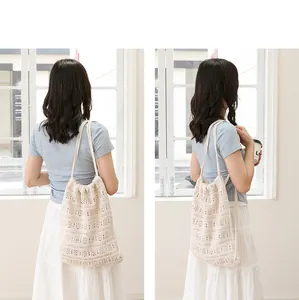 Vista trasera de una modelo con un bolso de ganchillo beige en una habitación clara