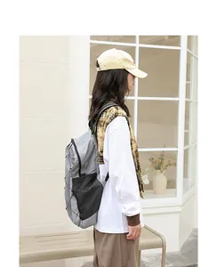Vista lateral de una mochila informal de nailon gris y negro llevada por una modelo en exteriores