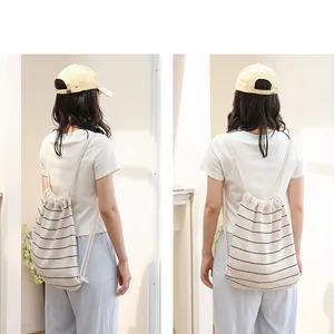 Rückansicht eines modischen gestreiften Strickrucksacks mit Kordelzug an einem Modell in Weiß.