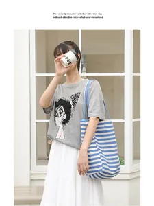 Detailed view of a stylish blue and white striped canvas tote bag carried by a model.