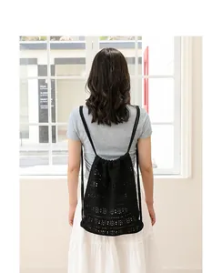 Vista trasera de mujer con mochila de algodón tejido calado negro con cordón.