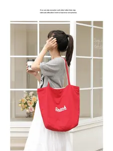 Vista detallada de un bolso tote de nailon rojo con estampado Beach llevado por una modelo urbana