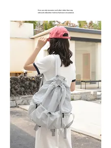 Back view of a casual light gray nylon drawstring backpack with pleated details