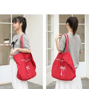 Rote Nylon-Einkaufstasche mit Palmenprint und ENJOY YOUR HOLIDAY-Slogan, Detailansicht.