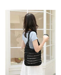 Lifestyle view of a trendy black hand-woven crochet hollow-out shoulder bag on a model