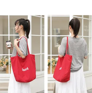 Bolso tote de nailon rojo con estampado Beach blanco llevado por una modelo de moda