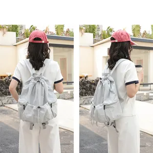 Detailed rear view of a casual gray nylon grid drawstring backpack worn by a model