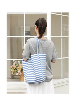 Casual blue and white striped canvas tote bag worn on shoulder in a cafe setting