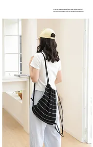 Detail eines schwarz-weiß gestreiften Strick-Rucksacks mit Kordelzug am Model.