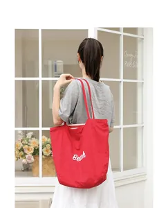 Vista trasera de una mujer con un bolso tote de nailon rojo con estampado Beach