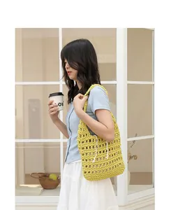 Detail view of yellow hand-woven cotton shoulder bag on a model in a cafe setting