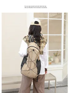 Vista trasera de una mochila de nailon caqui con bolsillos de malla en un modelo afuera