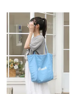 Elegante bolso tote de nailon azul claro con estampado Beach en un entorno de cafetería