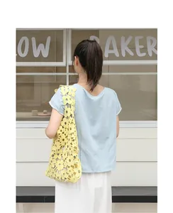 Detail view of a yellow hollow-out crochet flower shoulder bag on model