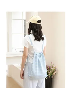 Modell mit einem hellblauen gestreiften Strick-Rucksack in einem hellen Innenraum.