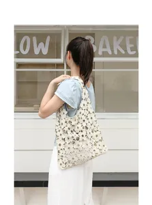 Close-up of cream floral hollow lace shoulder bag on Asian female model in casual setting.